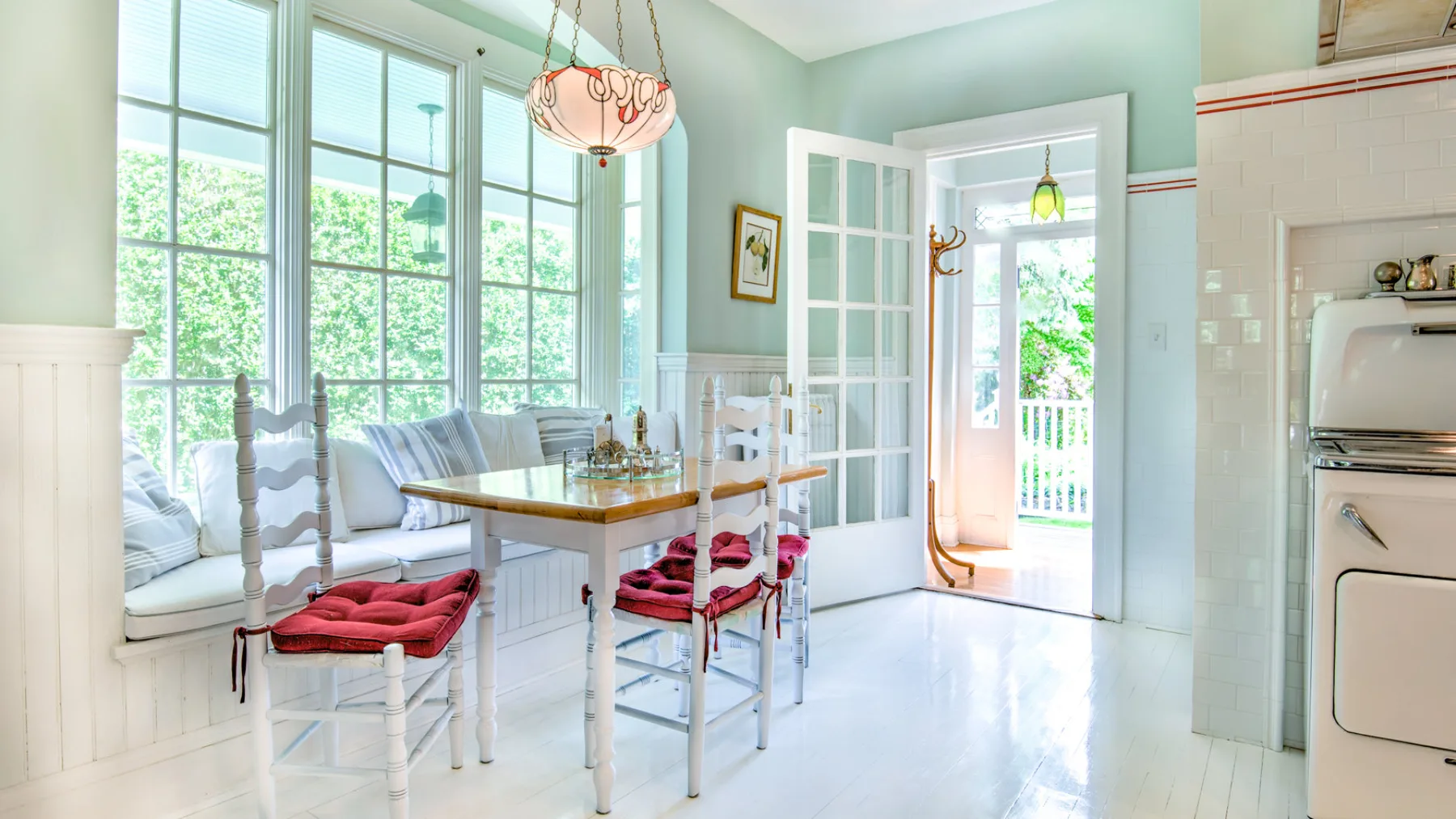 A bright dining area with a table beside large windows and an open doorway.