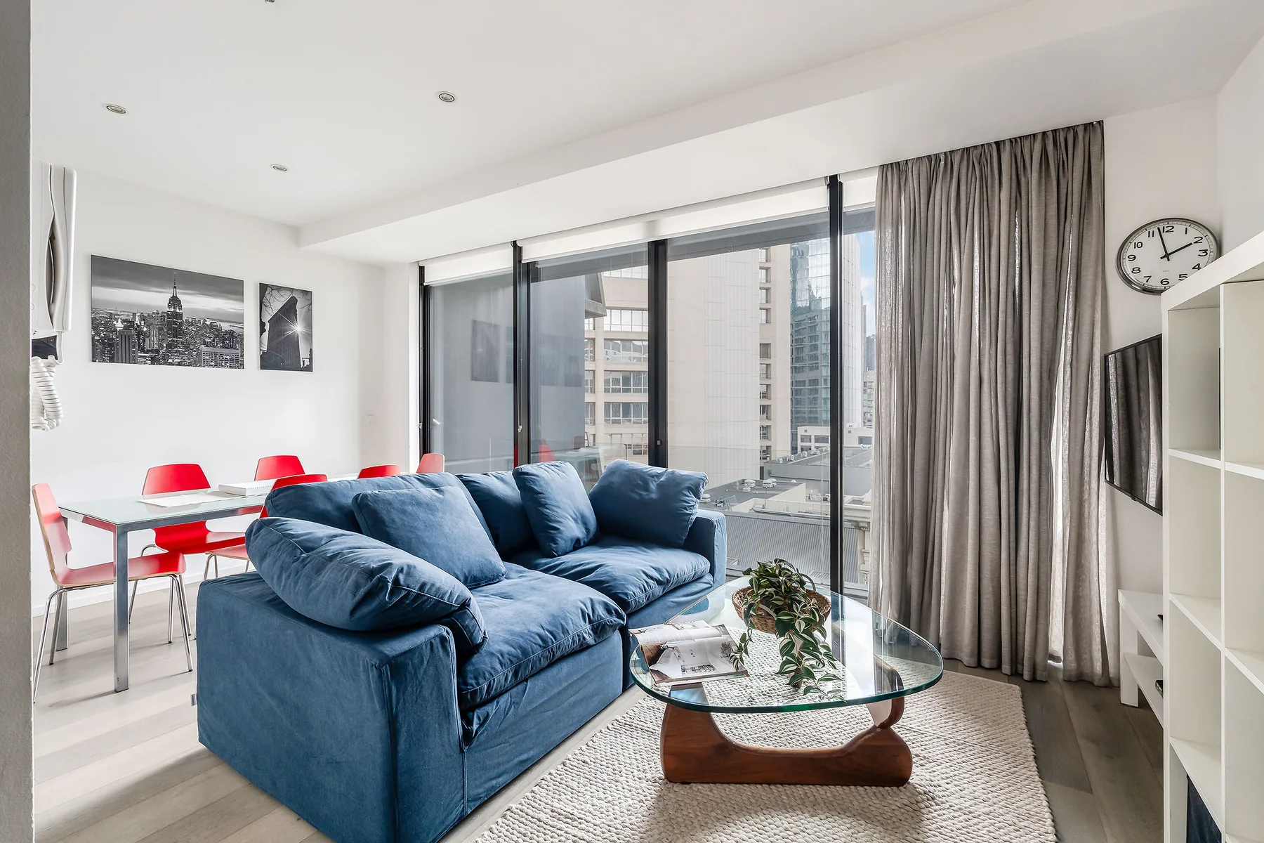 An open-plan living and dining area features blue seating beside large windows.