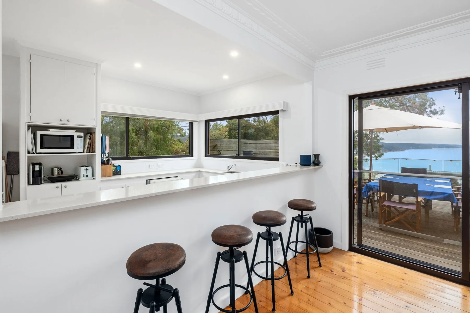 Una cocina luminosa con una barra y taburetes junto a puertas de vidrio que dan a un patio.