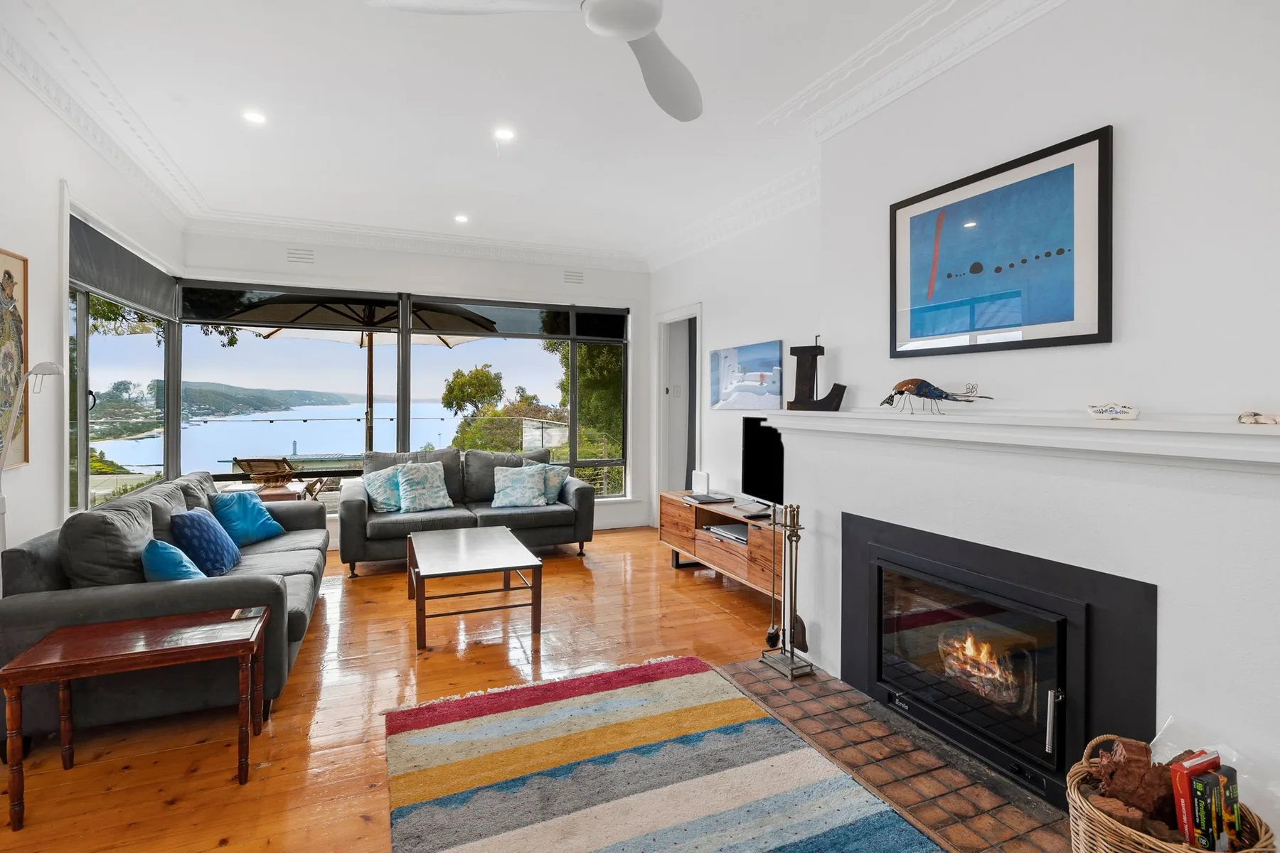 Sala de estar con asientos, una chimenea y amplias ventanas con vistas al agua.