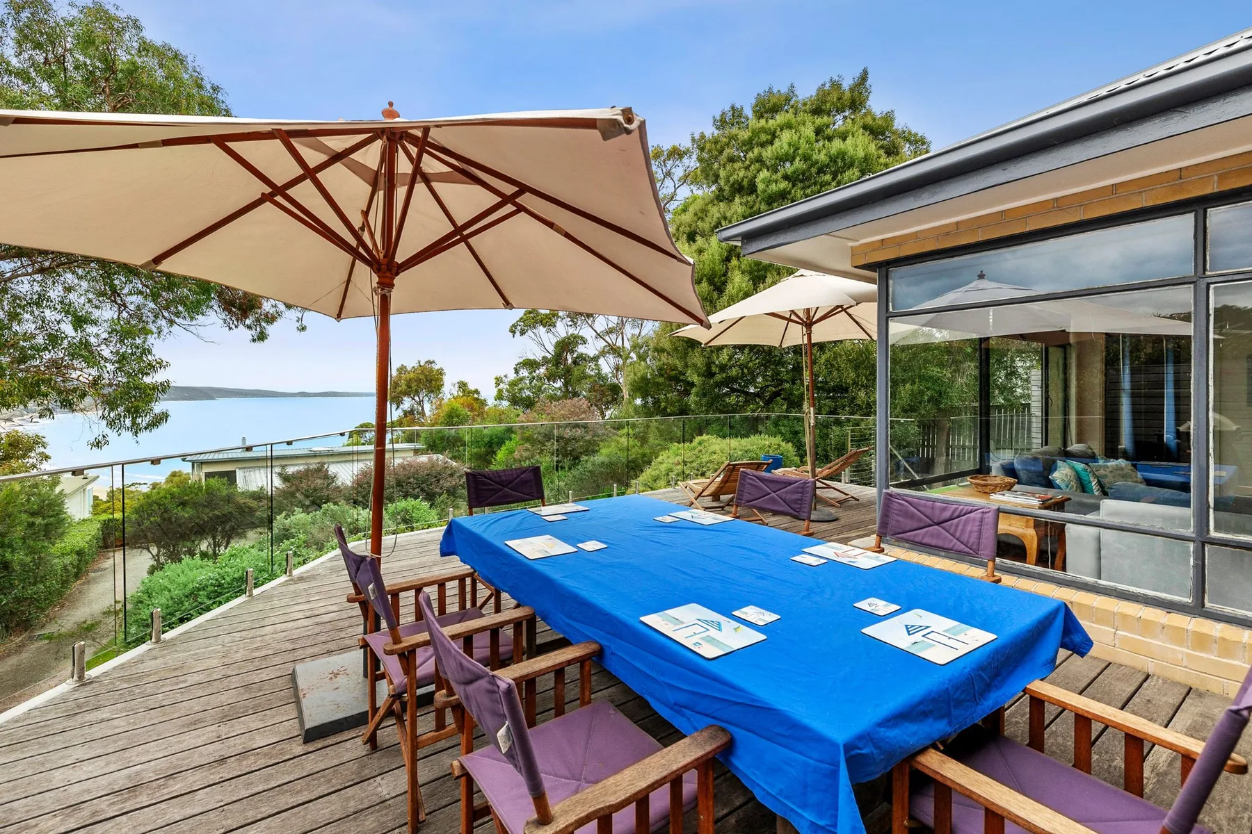 Comedor exterior cubierto con una mesa larga y sillas sobre una terraza.