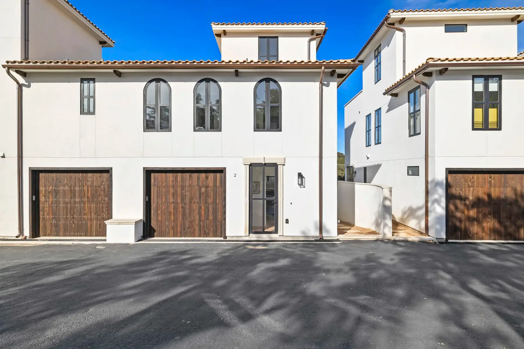 White multi-story residential buildings with arched upper windows and brown garage doors.