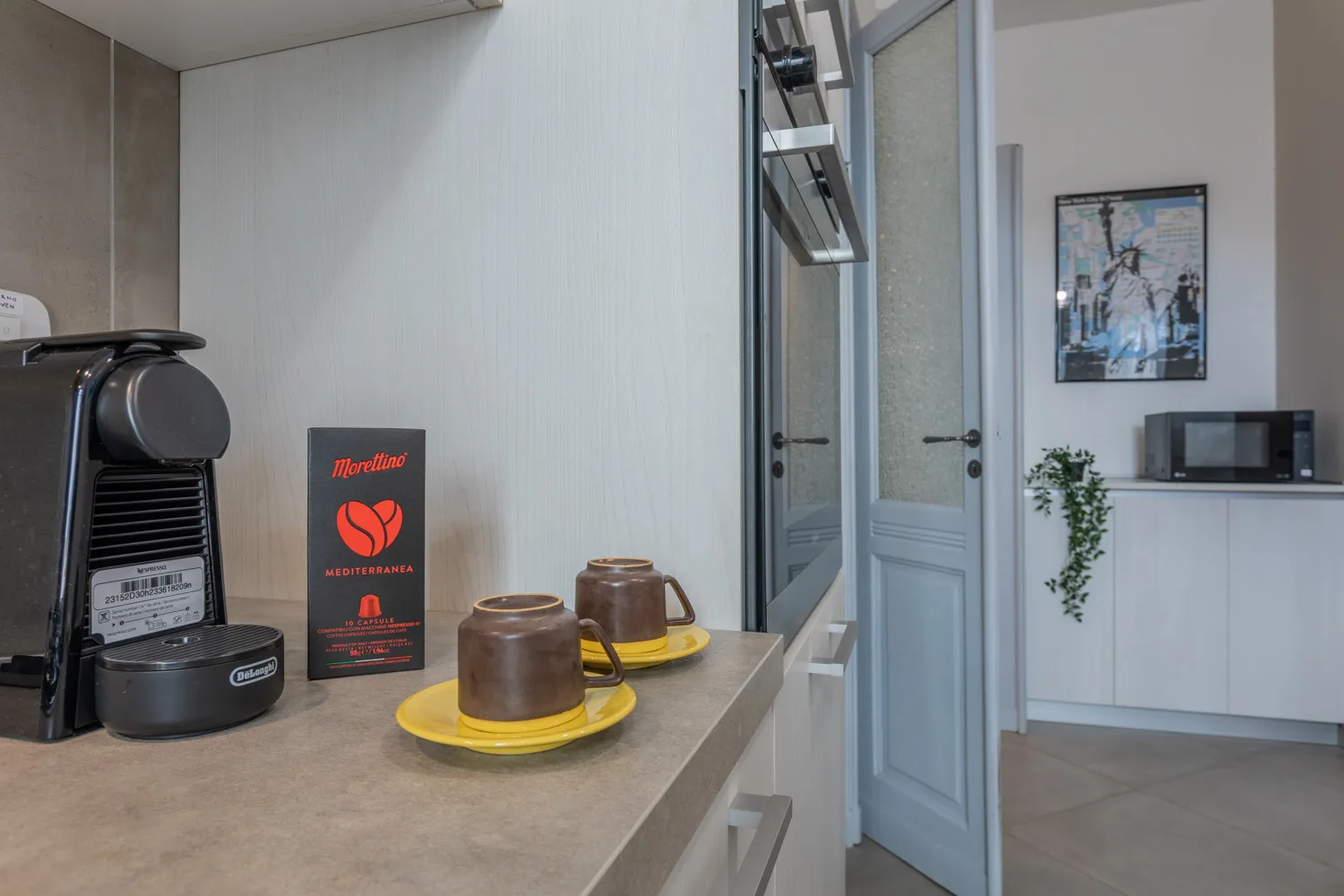 Una estancia con una cafetera y tazas sobre una encimera junto a puertas azul claro.