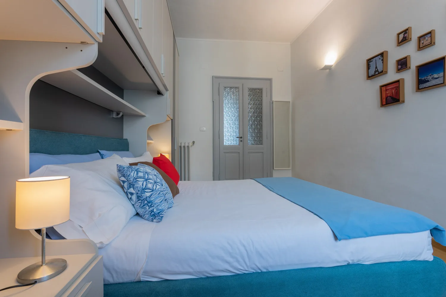Un dormitorio con una cama bien tendida y cuadros en la pared.