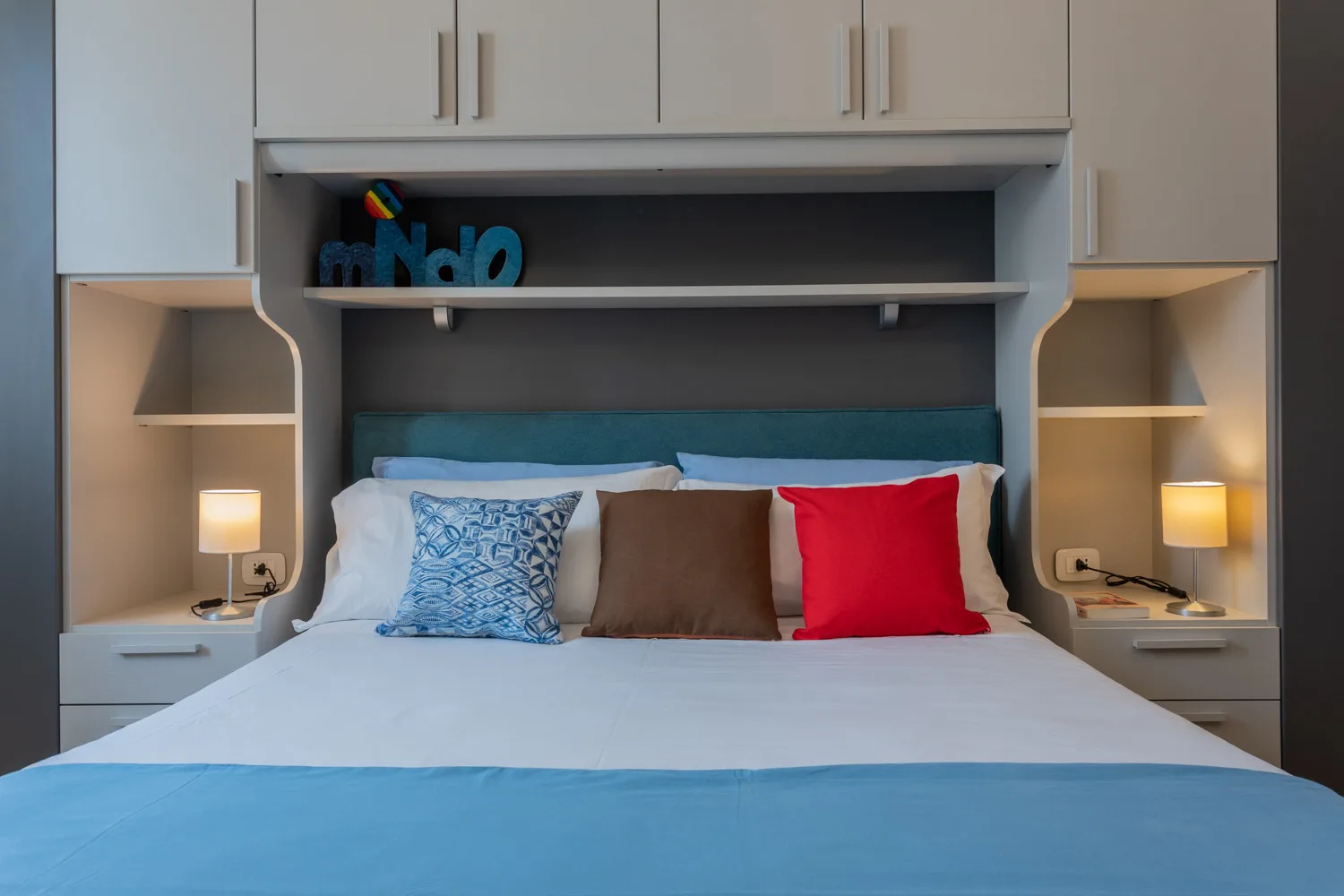 Un dormitorio con una cama tendida y cojines decorativos de colores.
