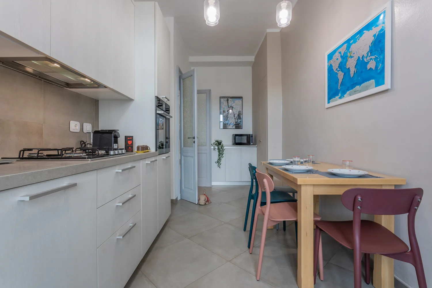 Una cocina estrecha con zona de comedor, encimera, mesa y sillas de colores.