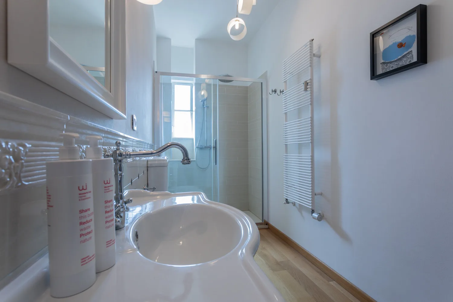 Un baño luminoso con un lavabo grande, un espejo de pared y una ducha de vidrio.
