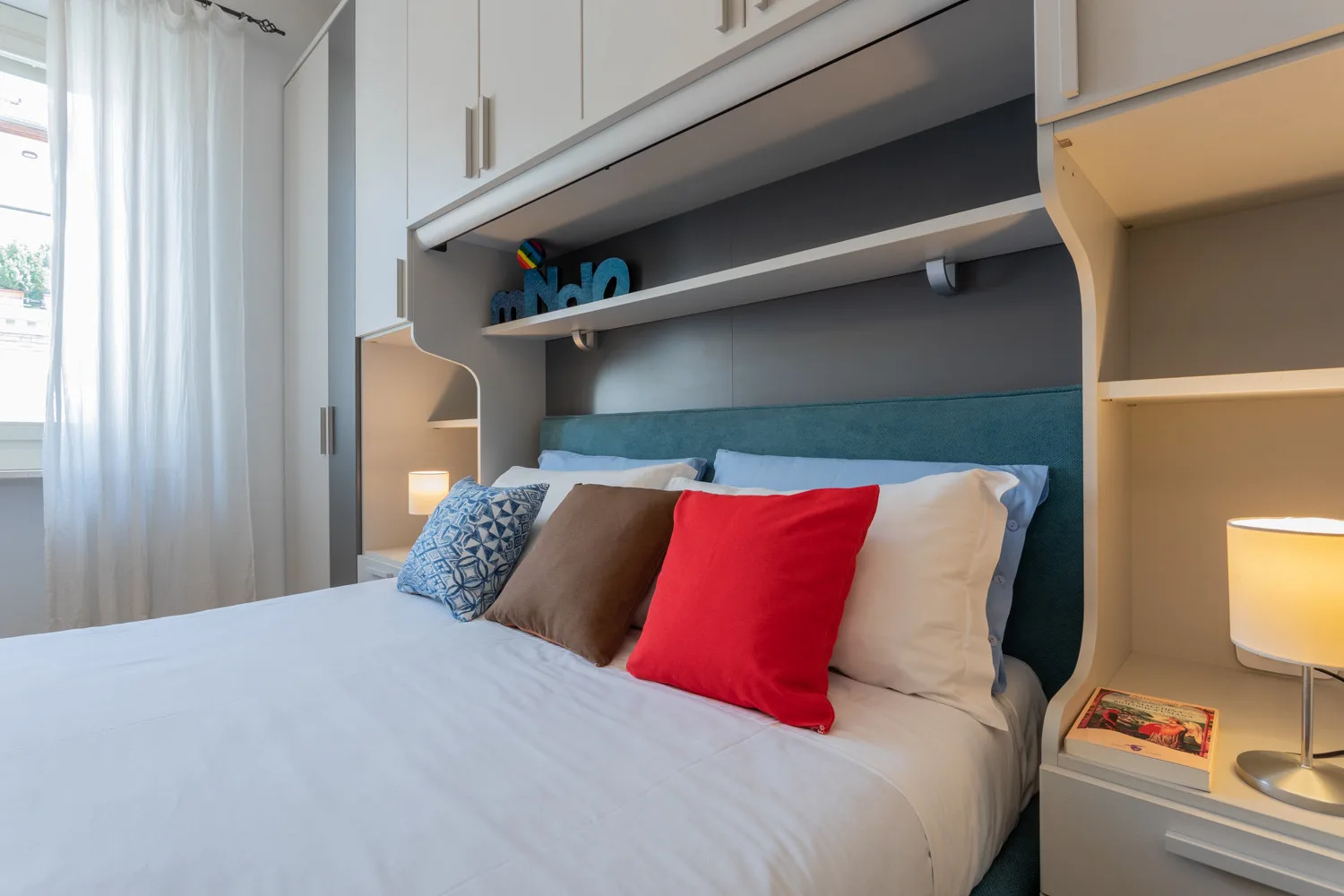 Un dormitorio con una cama bien tendida, cojines de colores y armarios empotrados.