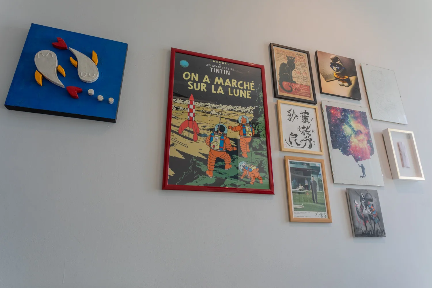 Una pared con una colección de láminas enmarcadas y obras de arte coloridas.