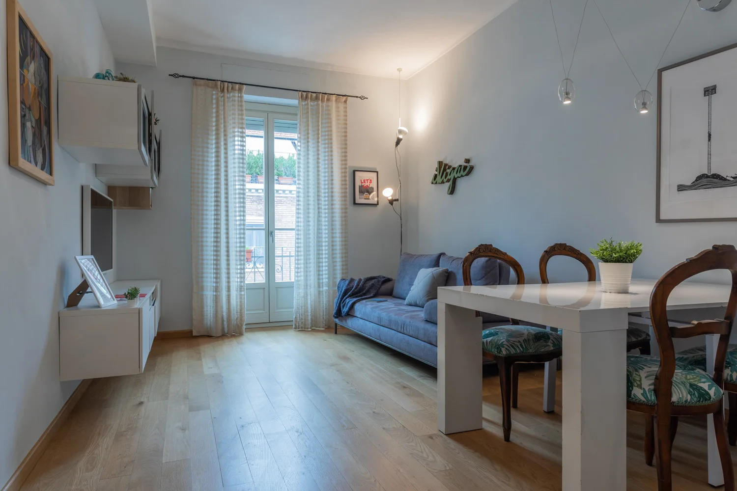Una zona de estar y comedor con asientos azules y una mesa junto a la ventana.
