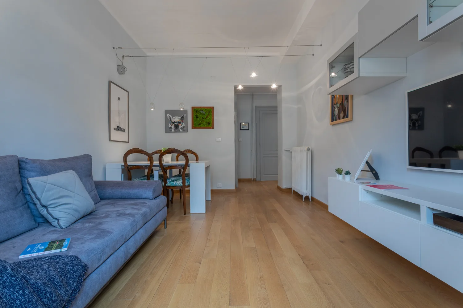 Una sala de estar con un sofá azul y un comedor.