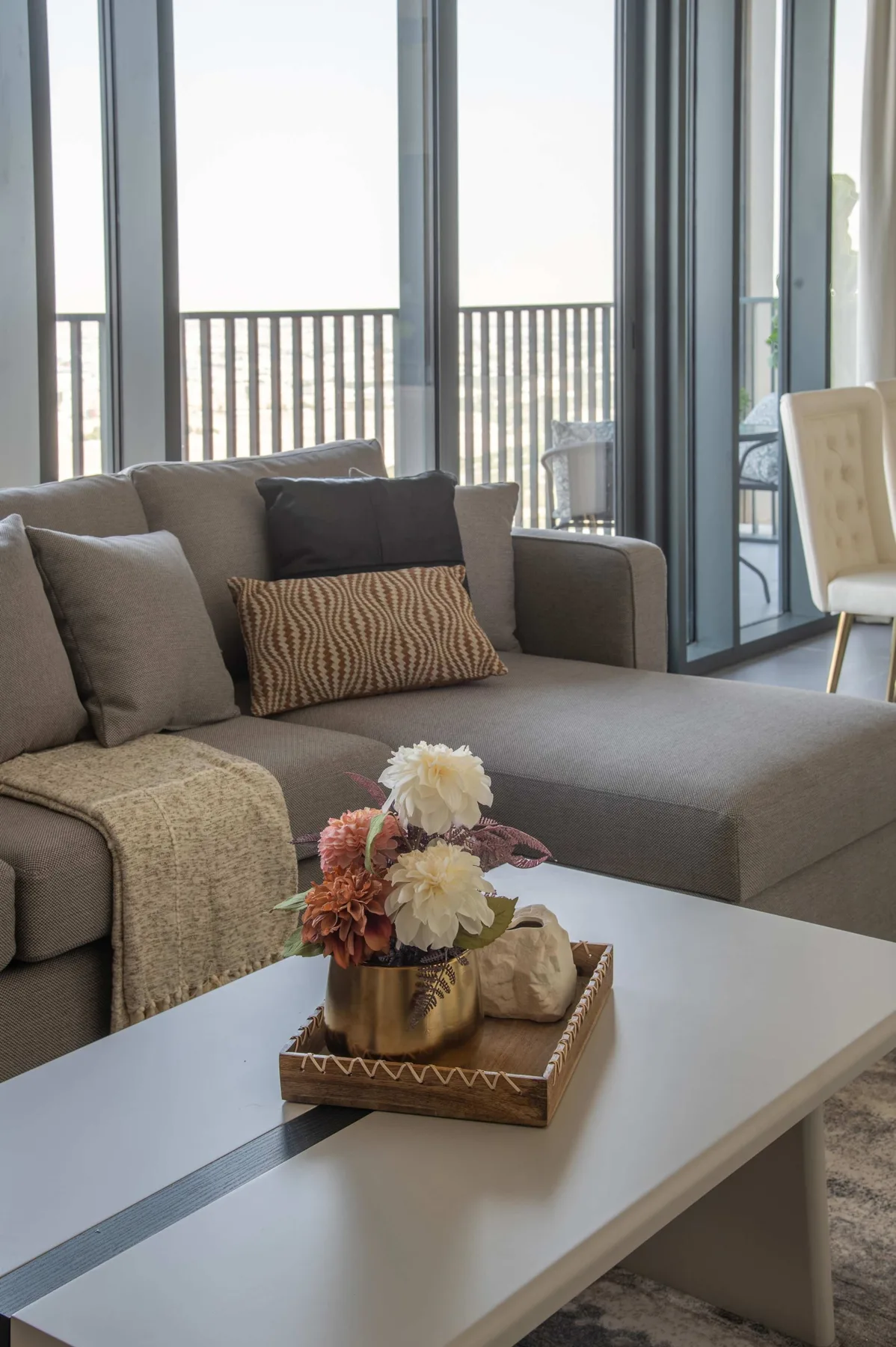 Una sala de estar con un sofá seccional gris y una mesa de centro con flores.