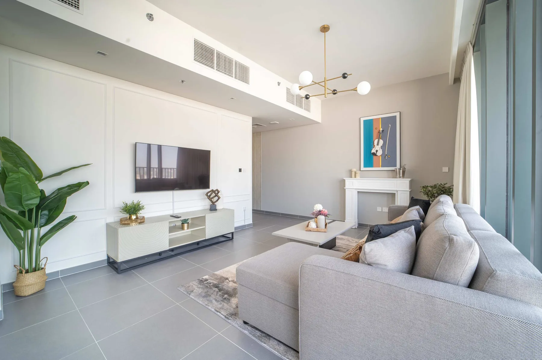 A bright living room with seating, a wall-mounted television, and a fireplace.