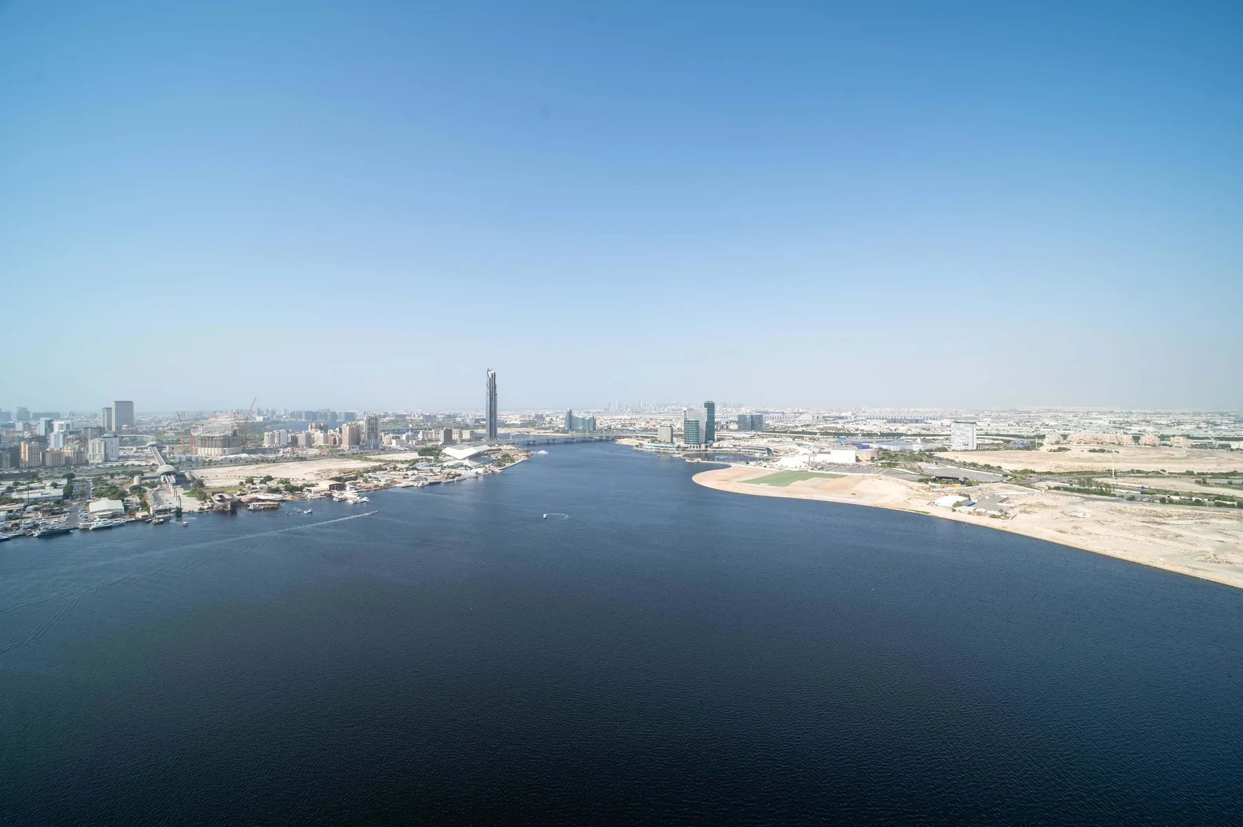 Un río ancho atraviesa la ciudad, con orillas arenosas bajo un cielo despejado.