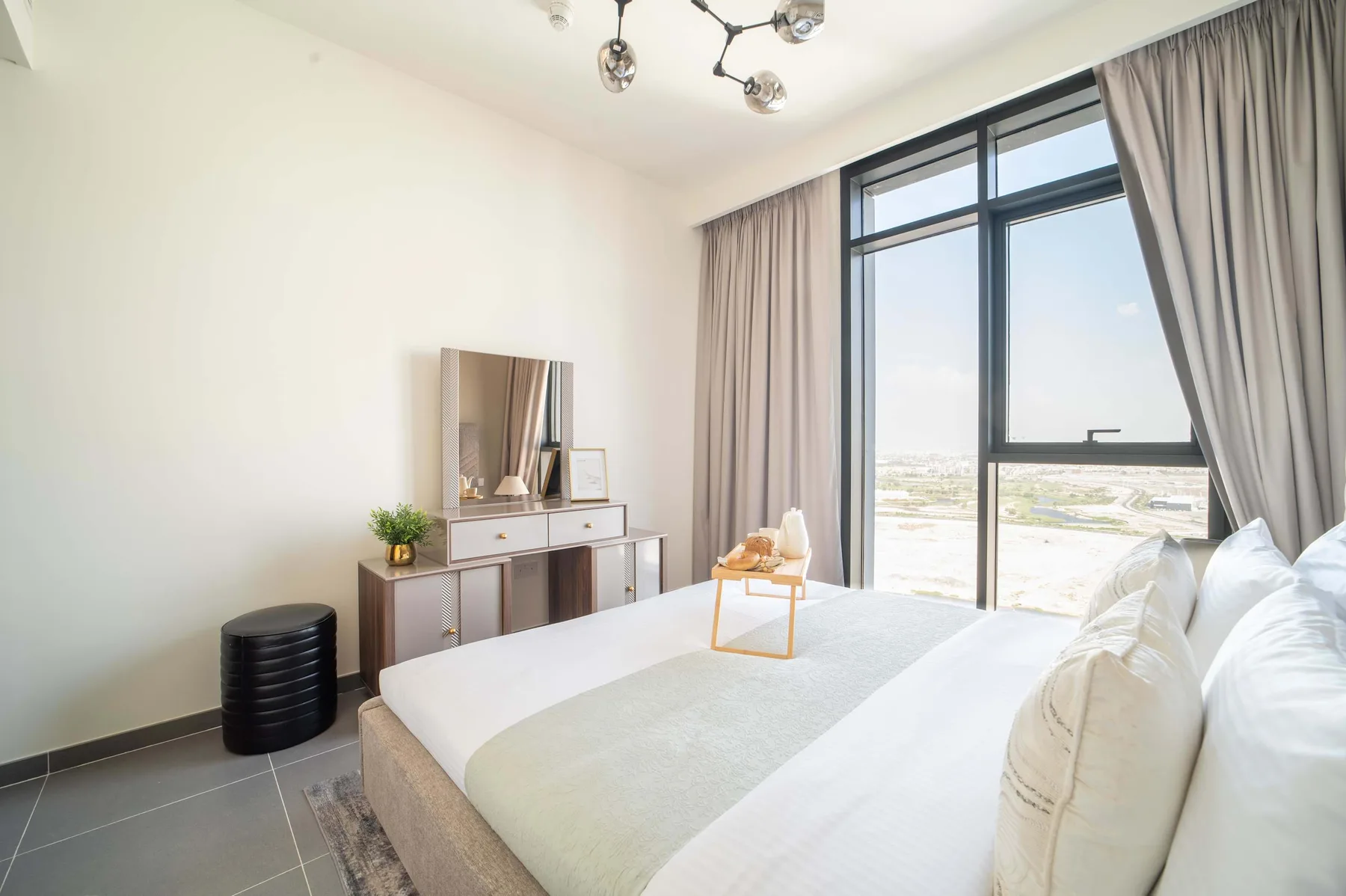 Un dormitorio luminoso con una cama bien arreglada junto a una ventana grande.