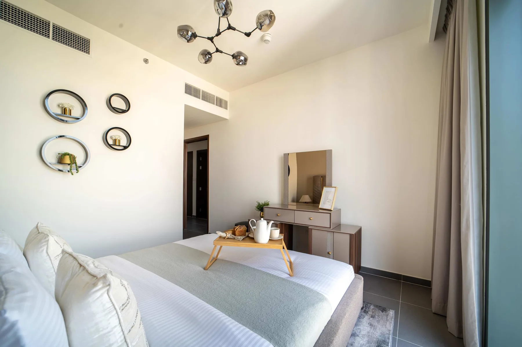 Un dormitorio luminoso con cama, mesita de noche y cortinas junto a la ventana.