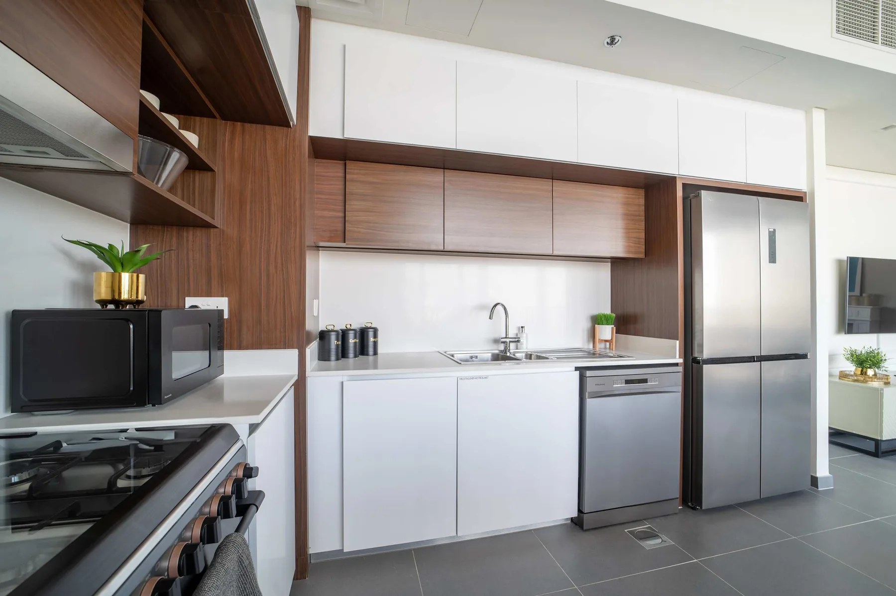 Una cocina moderna con armarios blancos, paneles de madera y electrodomésticos de acero inoxidable.