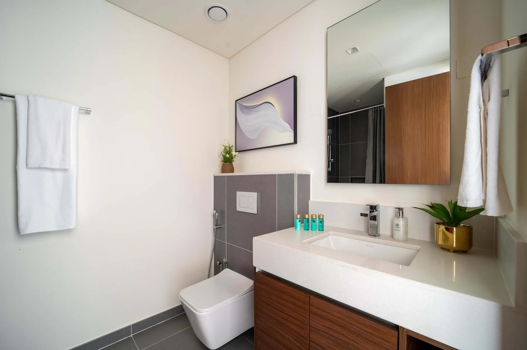Un baño con lavabo blanco, mueble de madera e inodoro.