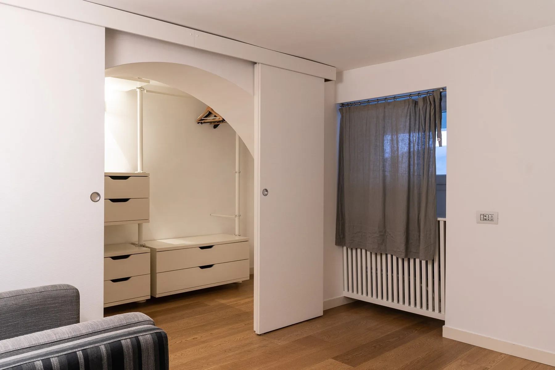 Un dormitorio con espacio de almacenamiento empotrado junto a una ventana con cortina.