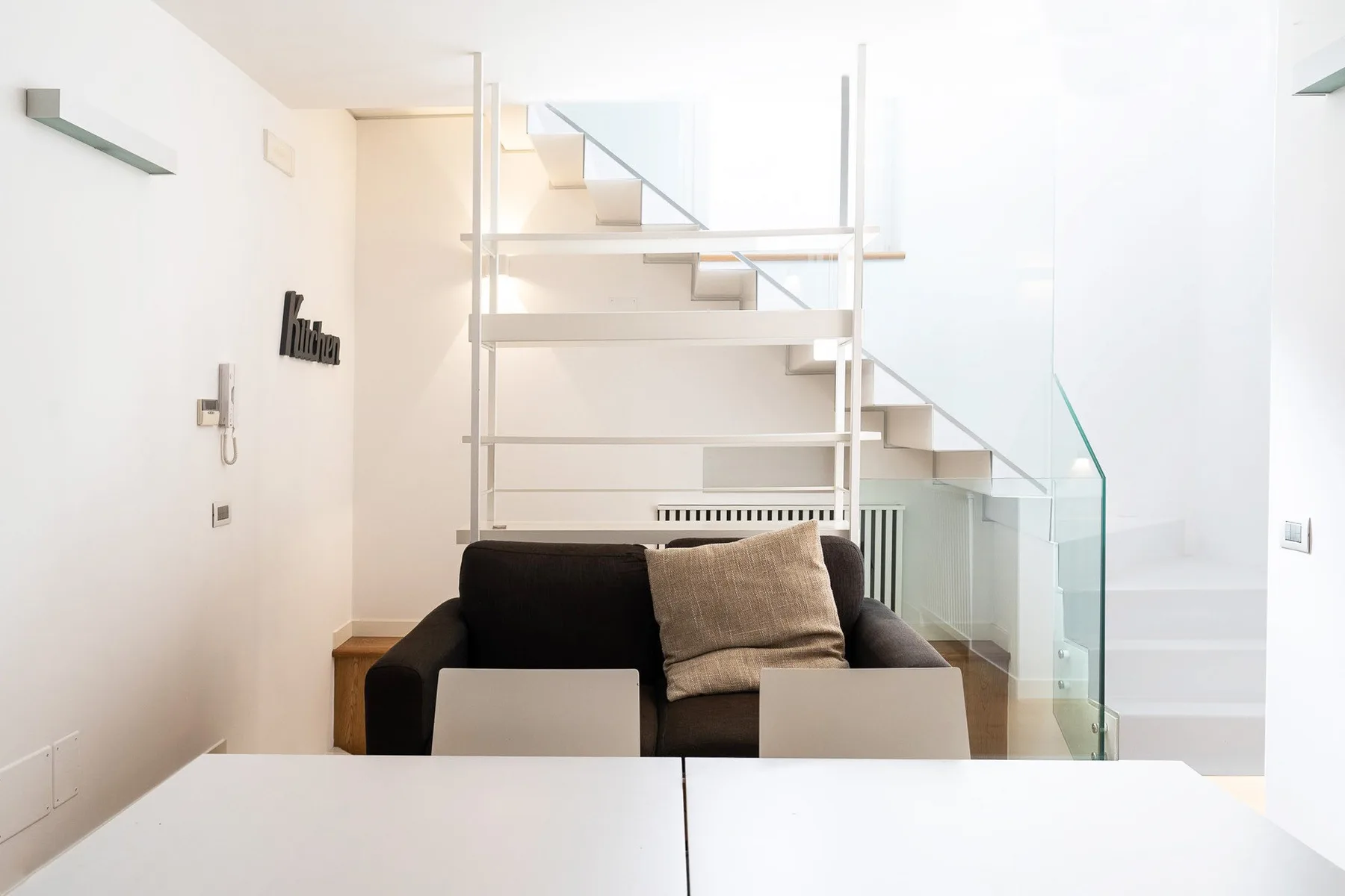 A bright living area with dark seating and a staircase behind it.