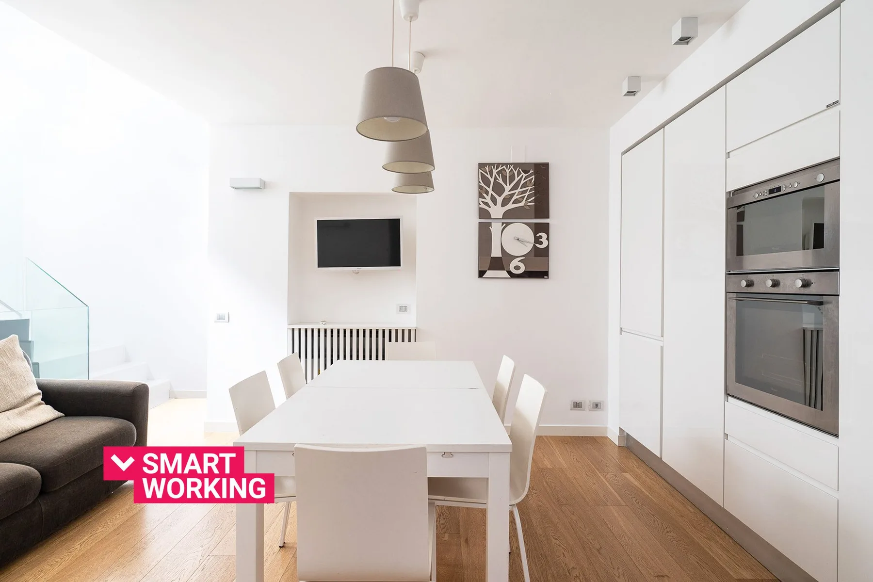 Un comedor luminoso con una mesa blanca, asientos y electrodomésticos integrados.