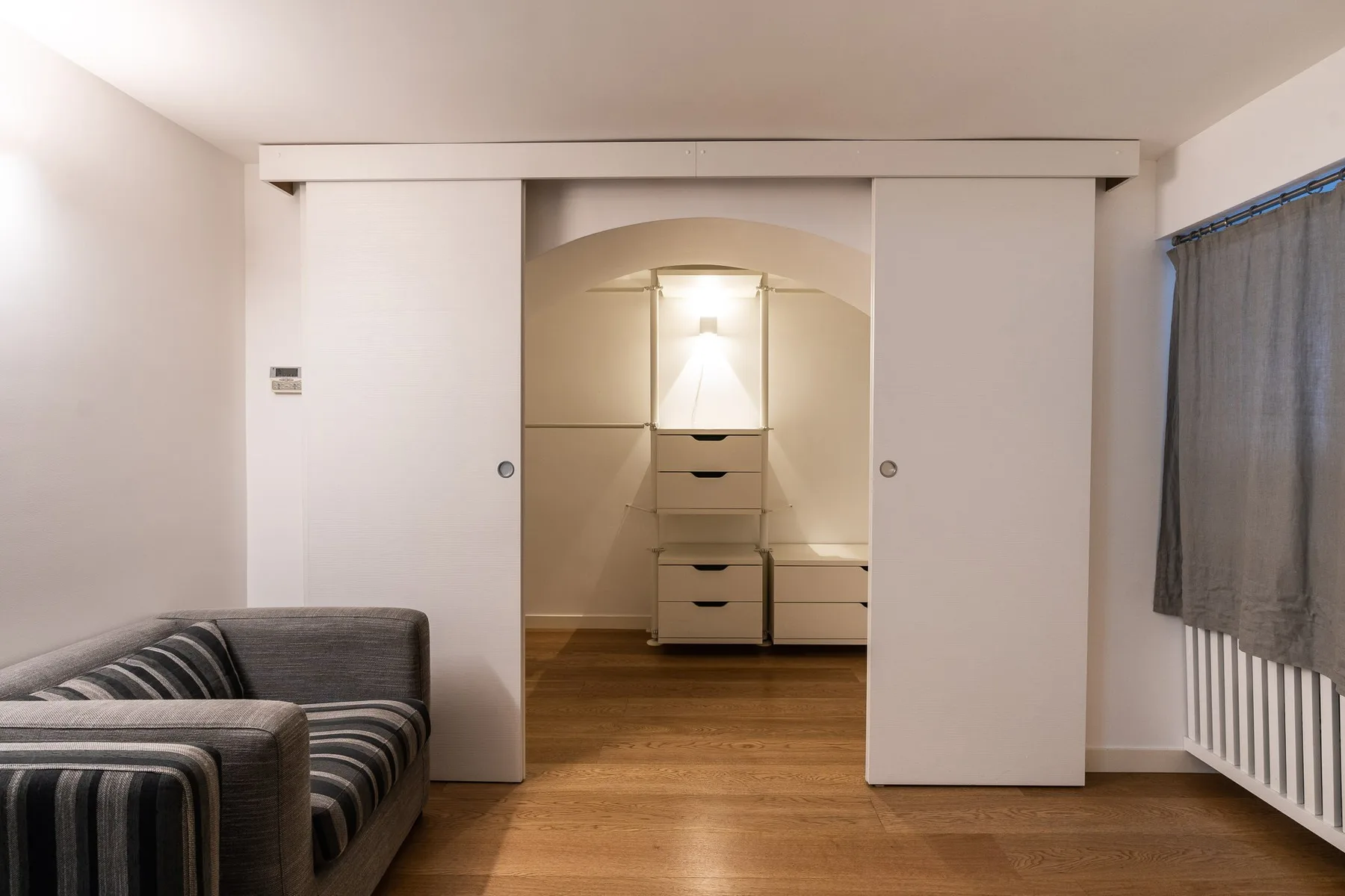 Un dormitorio con puertas corredizas de armario, cajones y una zona de asientos a rayas.