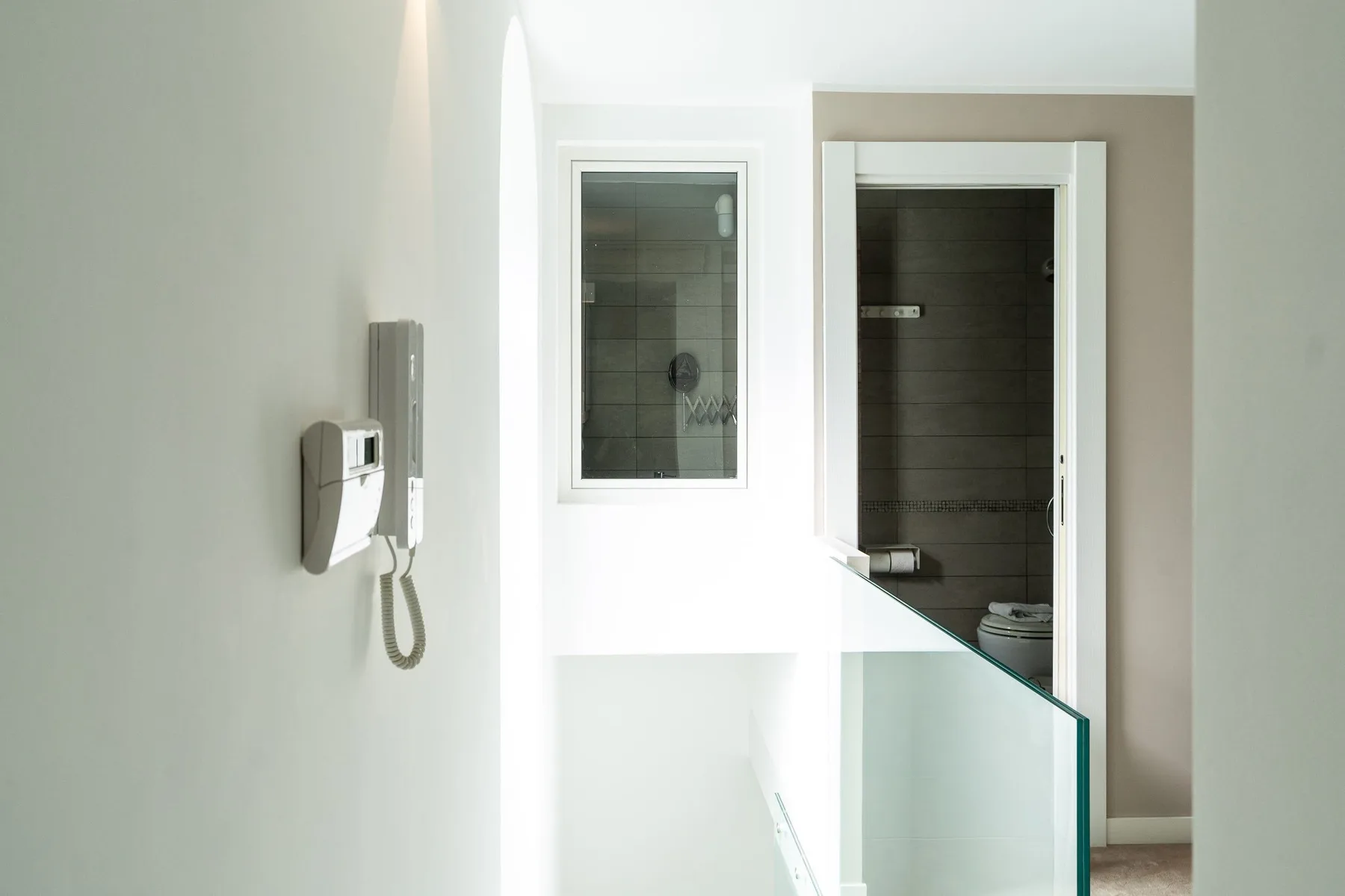 Un baño luminoso con una mampara de vidrio y un inodoro visible a través de la puerta.
