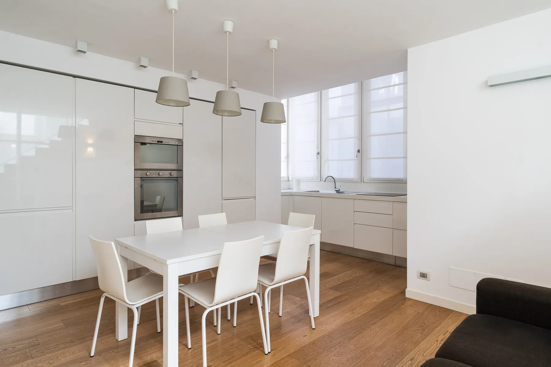 Una cocina y comedor luminosos y modernos, con una mesa blanca y sillas.