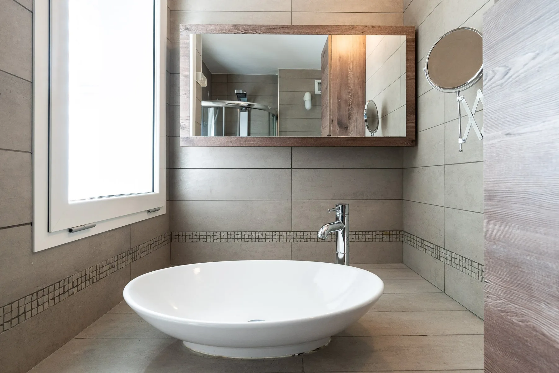 Un baño con un lavabo blanco bajo un armario de pared con espejo.