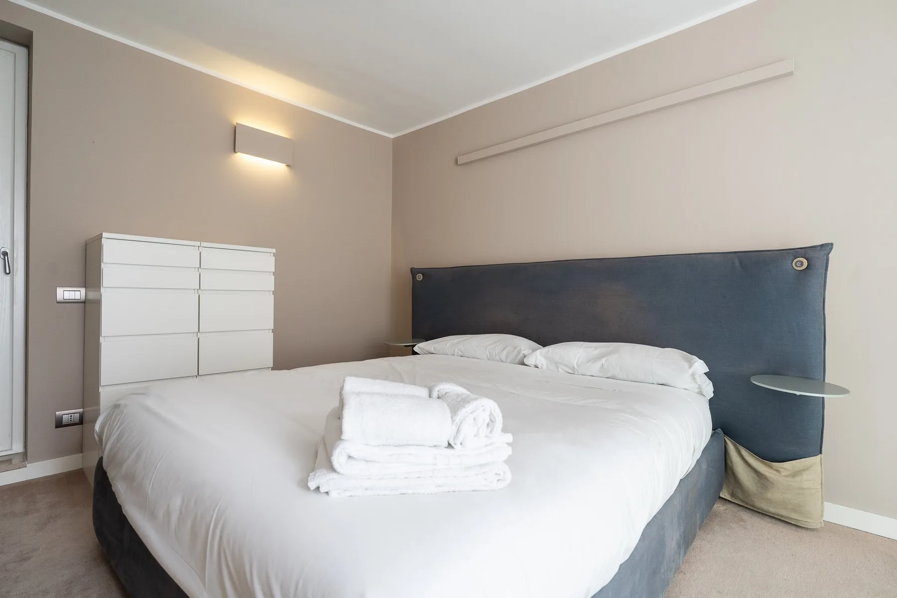 Un dormitorio con una cama bien hecha y toallas dobladas encima.