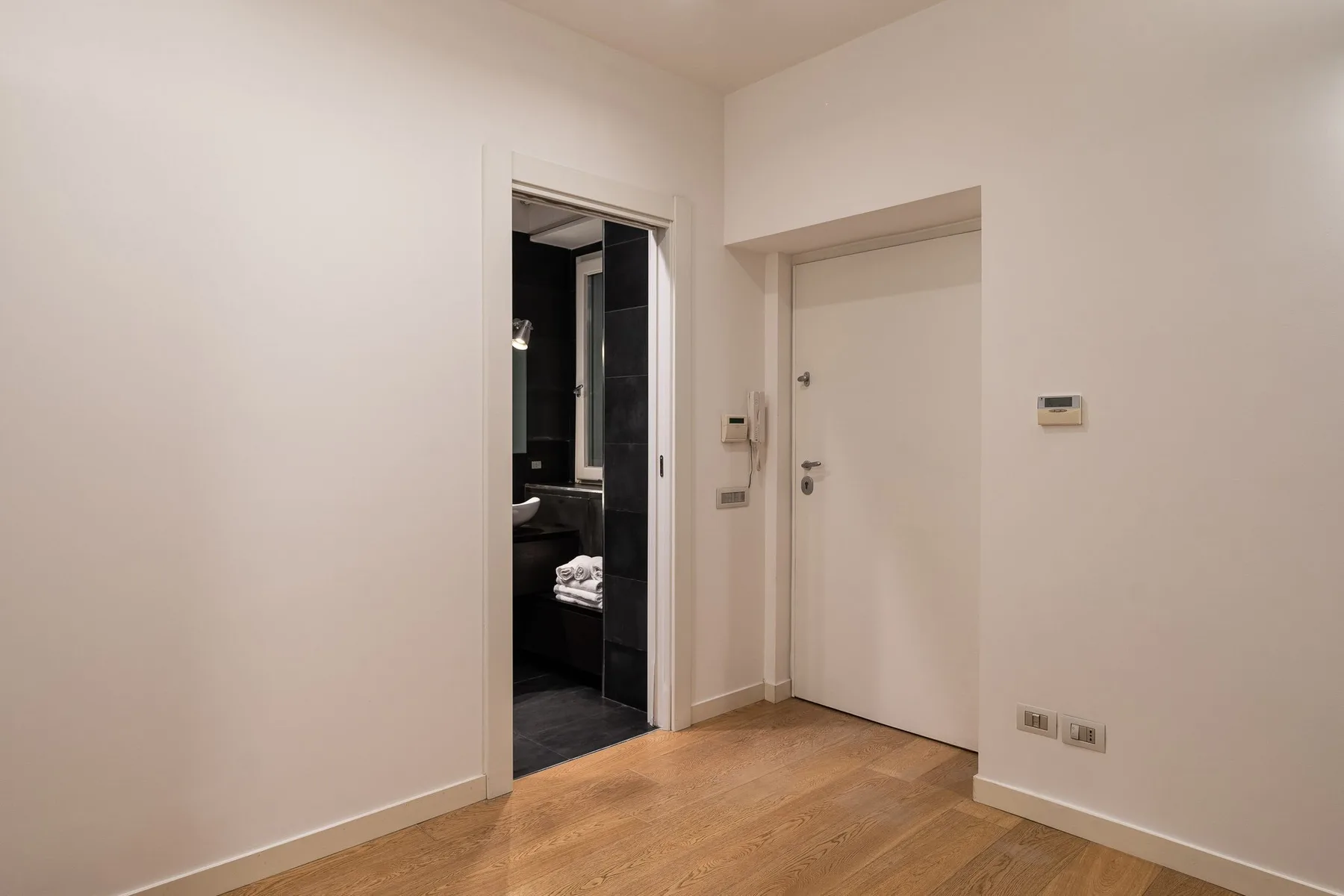 Una habitación vacía con suelo de madera y una puerta abierta al baño.