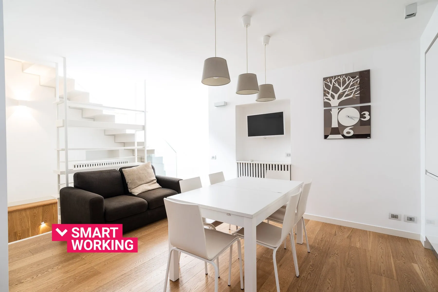 A bright living and dining area with a white table and dark seating.