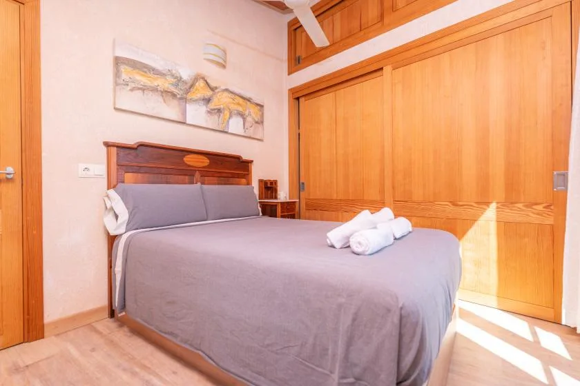 Un dormitorio con una cama bien tendida y puertas de armario de madera.