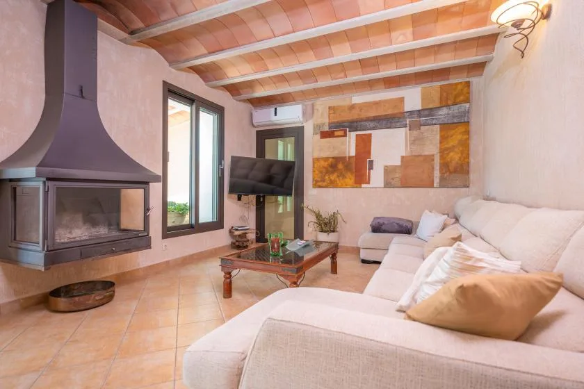 Una sala de estar con chimenea, televisor y asientos de color claro.