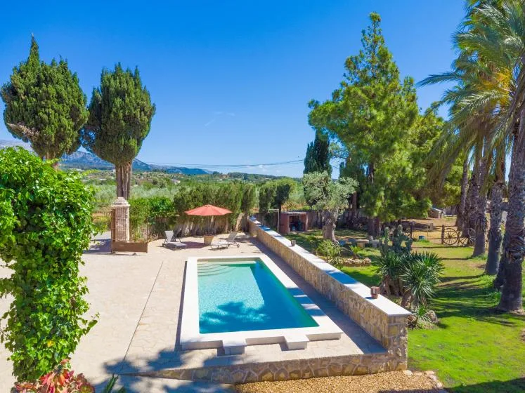 Una piscina está junto a un patio pavimentado y un jardín ajardinado.