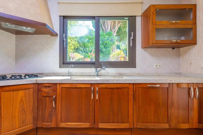 Una cocina con gabinetes de madera, una encimera y una ventana sobre el fregadero.