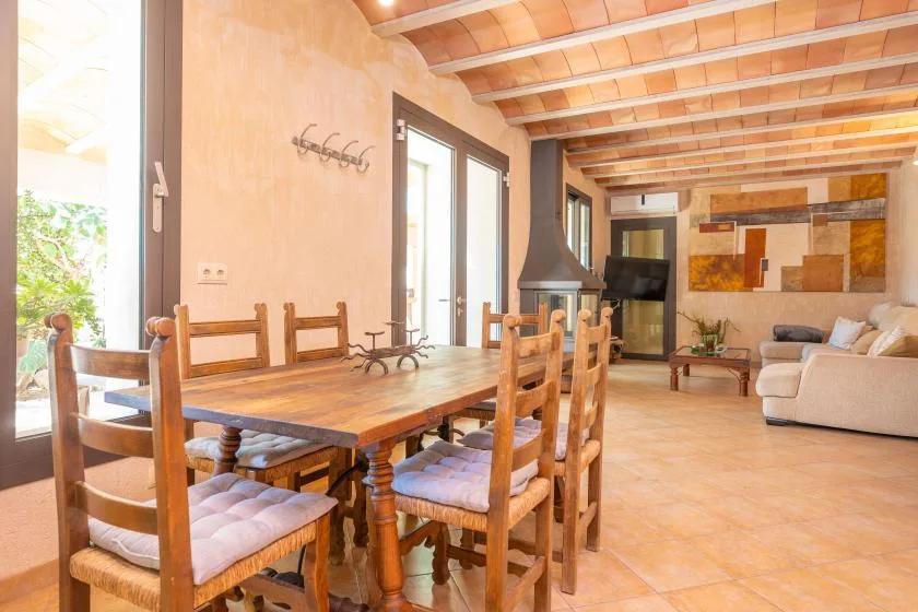 Un comedor con una mesa y sillas de madera junto a una sala de estar.