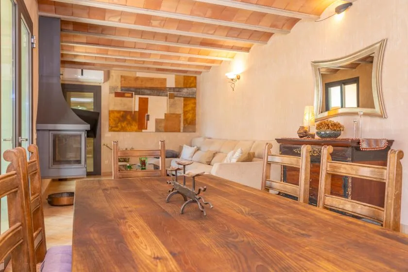 Una sala de estar con una mesa grande de madera y asientos junto a una chimenea.