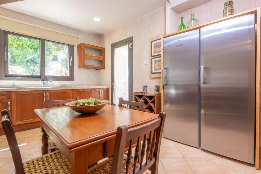 Una cocina y comedor con una mesa de madera junto a refrigeradores de acero inoxidable.