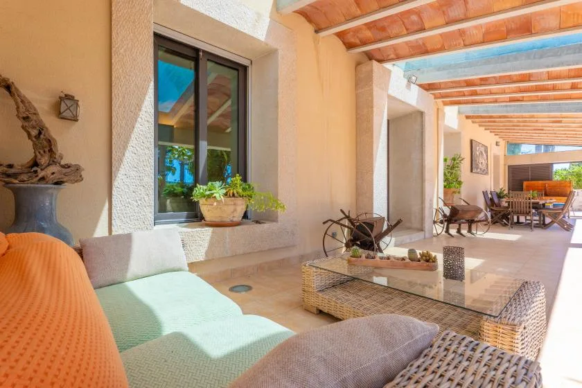 Un patio cubierto con asientos acolchados y una mesa baja.