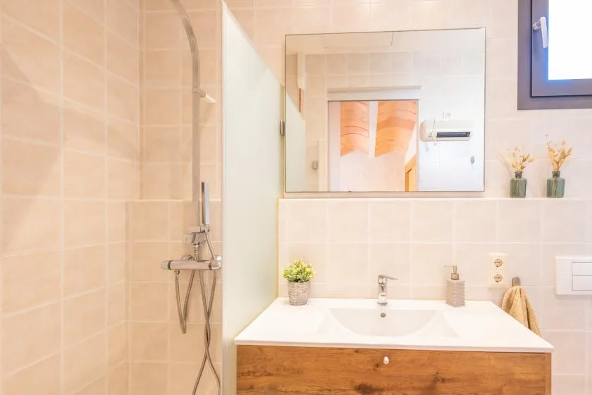 Un baño alicatado con lavabo y accesorios de ducha en la pared.