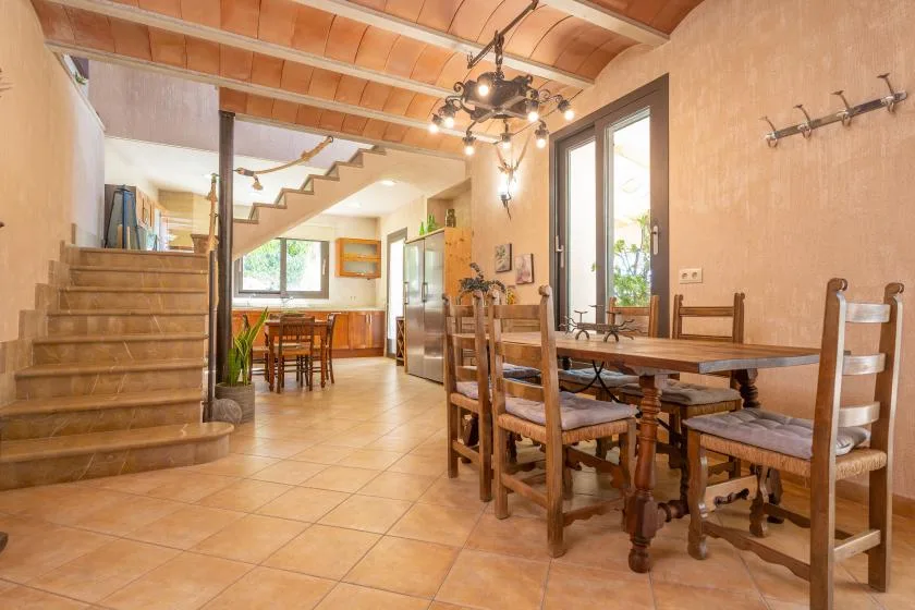 Un comedor con una mesa y sillas de madera bajo vigas de techo expuestas.