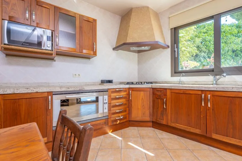 Una cocina con armarios de madera, una encimera y una ventana con vistas a la vegetación.