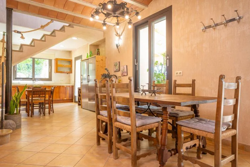 Un comedor con una mesa de madera y asientos, junto a una cocina abierta.