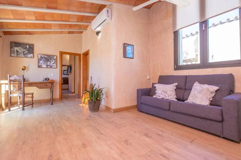 Una sala de estar con un sofá bajo una ventana grande y una pequeña zona de comedor.