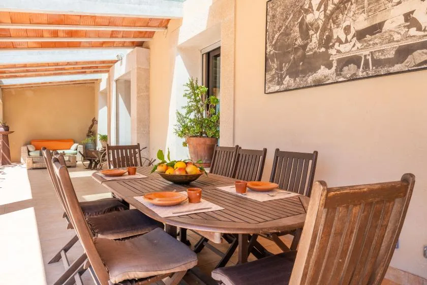 Comedor de patio soleado con una mesa larga de madera y sillas.