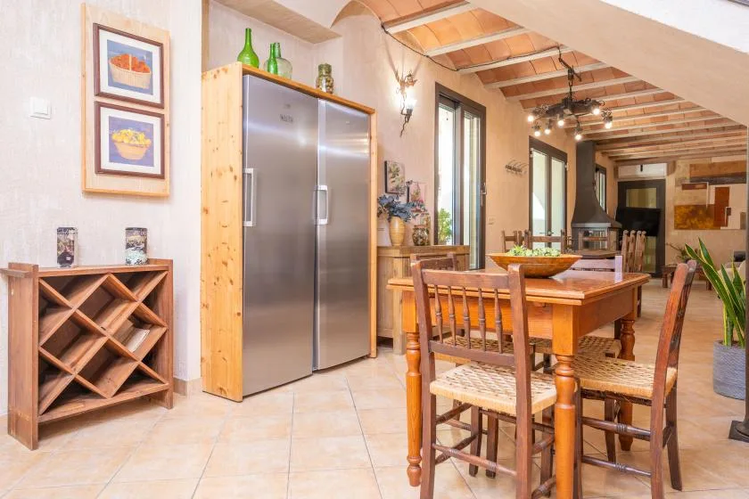 Un comedor con una mesa y sillas de madera junto a un refrigerador.