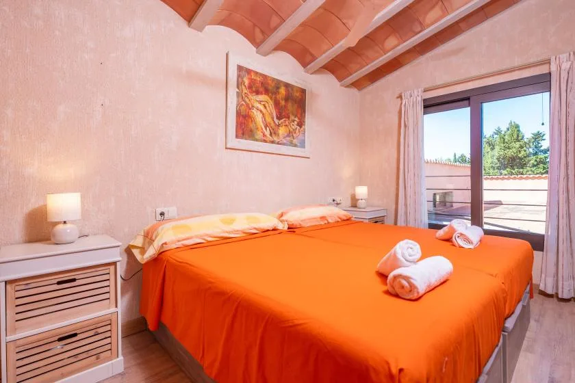 Un dormitorio con una cama grande cubierta con ropa de cama naranja brillante.