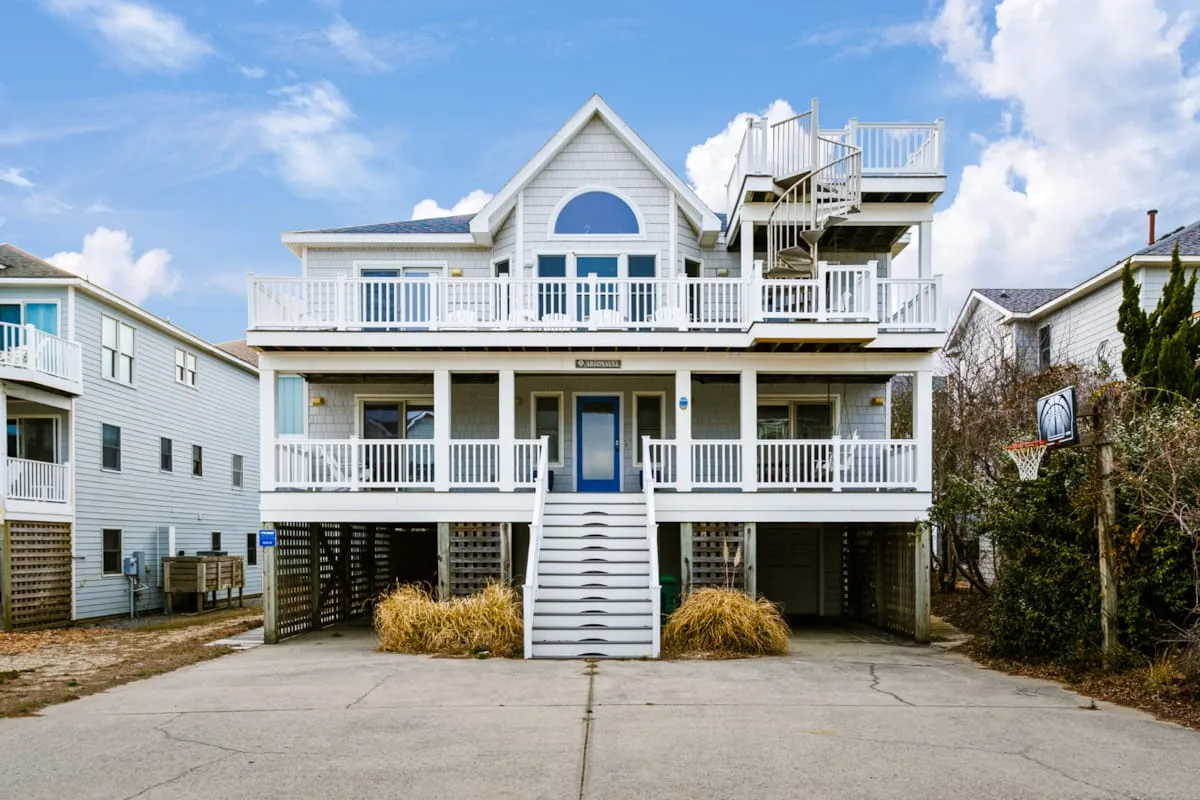 Una casa grande con balcones blancos y una escalera central.