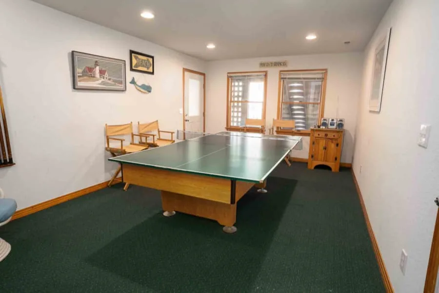 Una sala de recreación con una mesa de ping-pong verde y sillas.